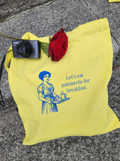 Close-up of blue feminist print on yellow canvas tote with a funny patriarchy joke by tantrm