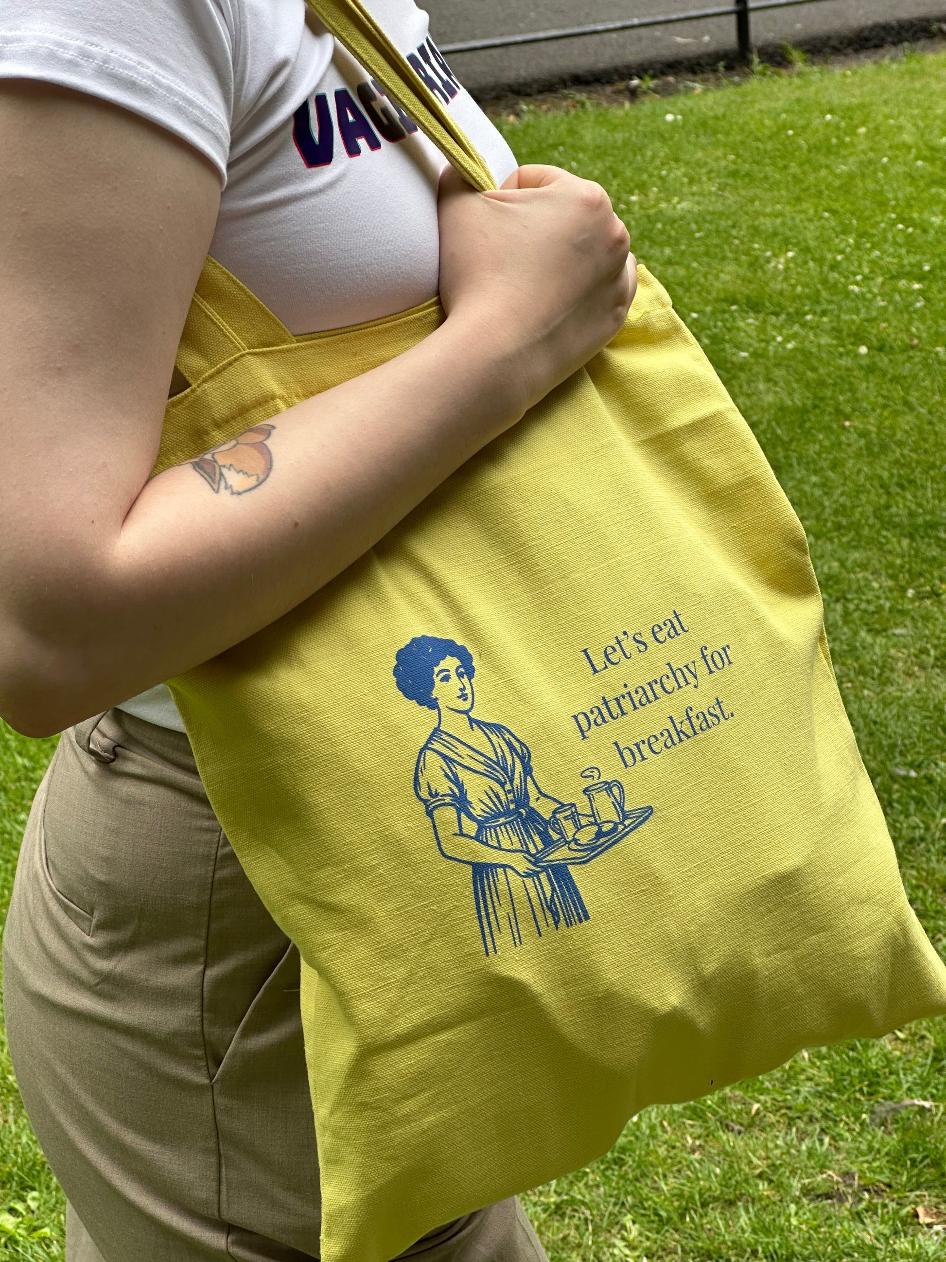 Yellow feminist tote bag with vintage woman holding breakfast tray and “Let’s eat patriarchy for breakfast” quote